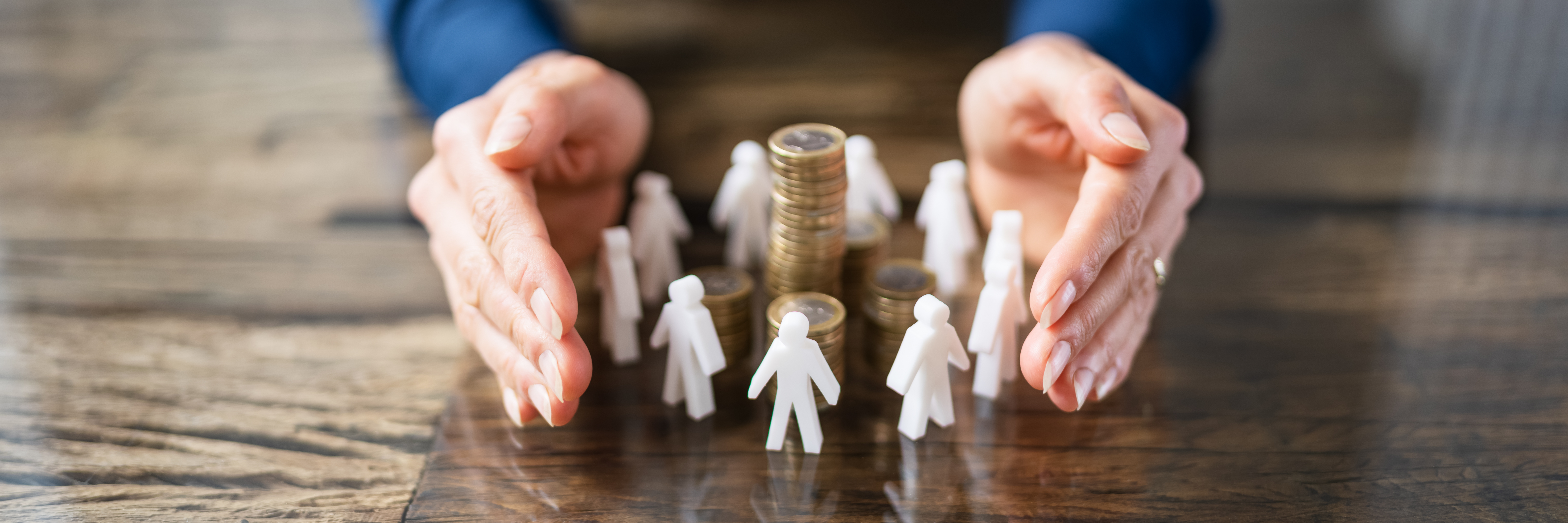 hands hugging little people figures and coins